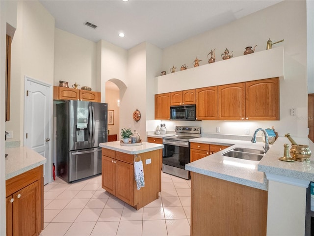 kitchen featuring a center island, sink, a towering ceiling, light tile patterned floors, and stainless steel appliances