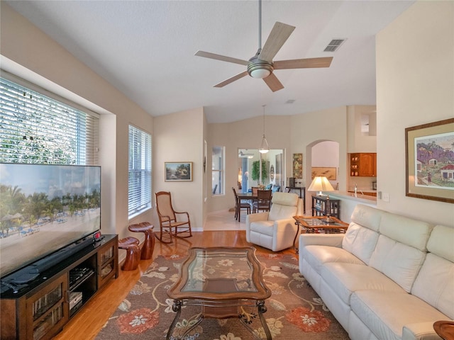 living room with ceiling fan, light wood-type flooring, and lofted ceiling