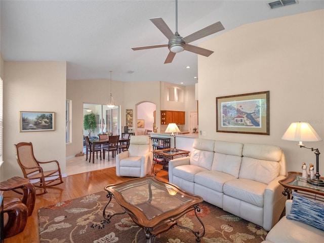 living room with ceiling fan, light hardwood / wood-style floors, and lofted ceiling