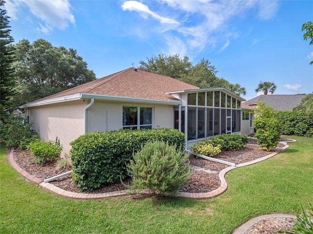 rear view of house featuring a lawn and a sunroom