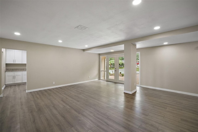 unfurnished living room with dark hardwood / wood-style flooring and french doors