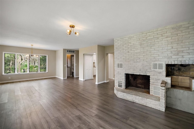 unfurnished living room with dark hardwood / wood-style flooring, a fireplace, and a chandelier