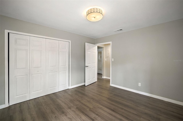 unfurnished bedroom featuring a closet and dark hardwood / wood-style flooring