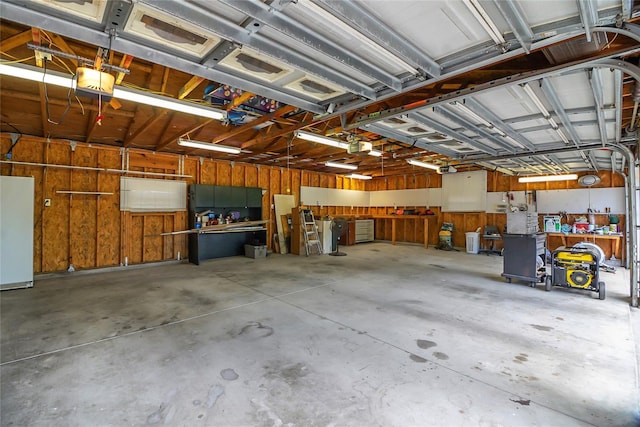 garage with a workshop area, wooden walls, a garage door opener, and white refrigerator