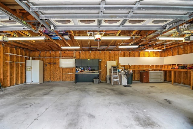 garage with wooden walls, white refrigerator with ice dispenser, and a garage door opener