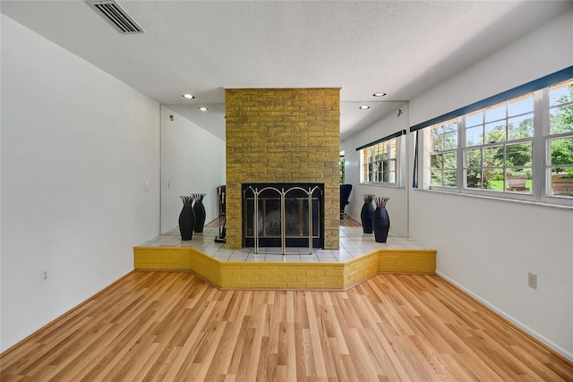 unfurnished living room featuring hardwood / wood-style floors, a fireplace, and a textured ceiling