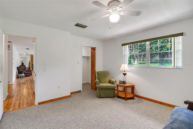 living area with carpet and ceiling fan