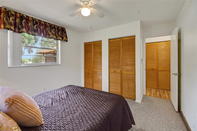 carpeted bedroom with ceiling fan and two closets