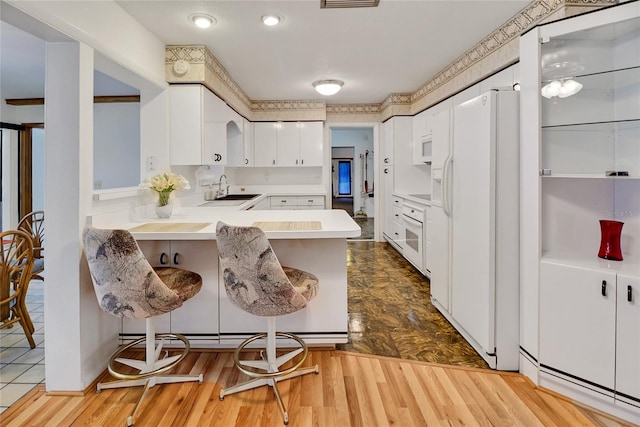 kitchen featuring kitchen peninsula, a kitchen breakfast bar, white appliances, light hardwood / wood-style flooring, and white cabinetry