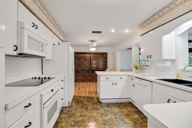 kitchen with white cabinets, white appliances, kitchen peninsula, and sink