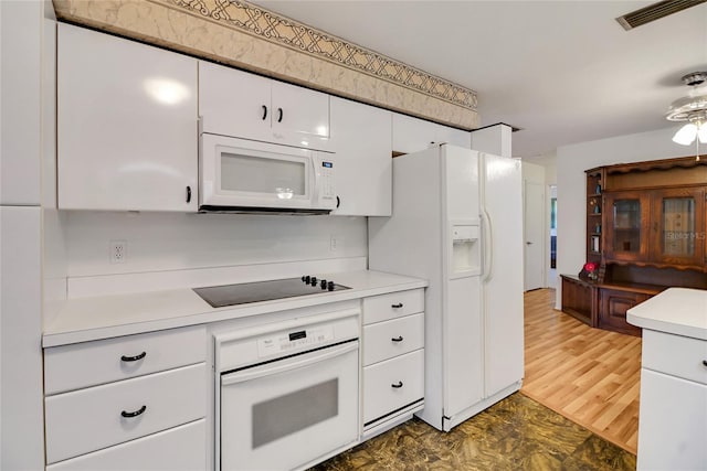 kitchen featuring white cabinetry, wood-type flooring, and white appliances