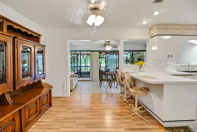 kitchen featuring white cabinets, sink, ceiling fan, light hardwood / wood-style floors, and kitchen peninsula