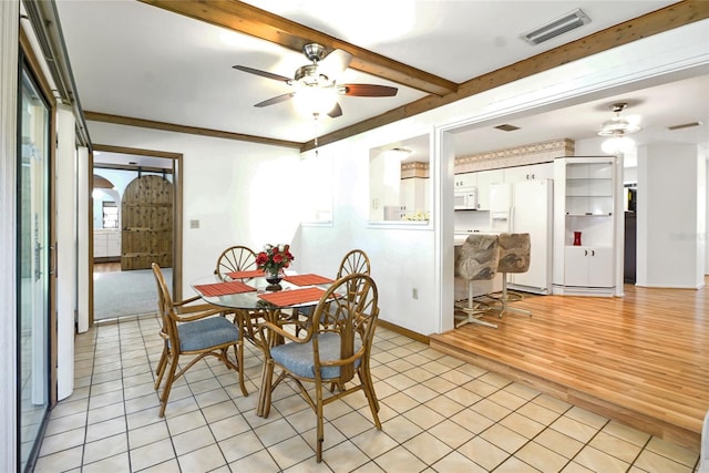 dining space with ceiling fan, beamed ceiling, ornamental molding, and light wood-type flooring