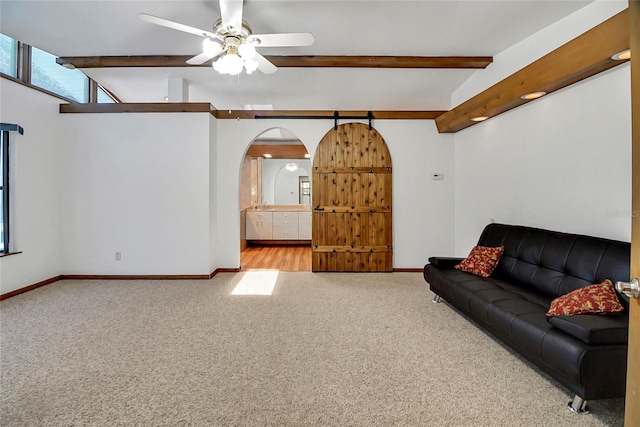 unfurnished living room featuring lofted ceiling with beams, ceiling fan, and light colored carpet