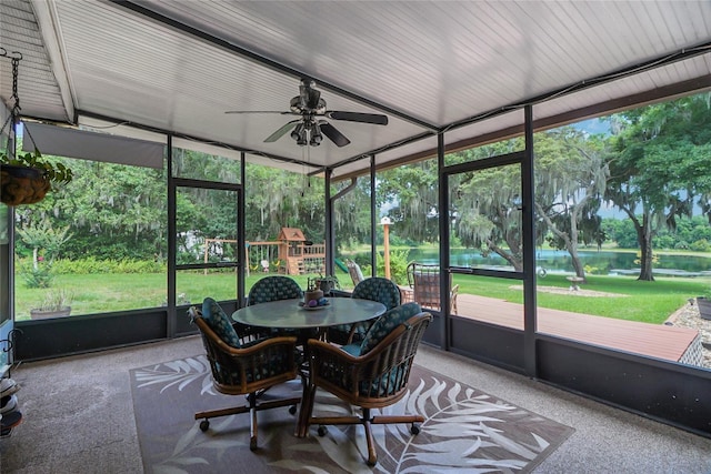 sunroom with ceiling fan and a water view