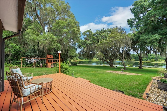 wooden deck featuring a playground, a water view, and a yard