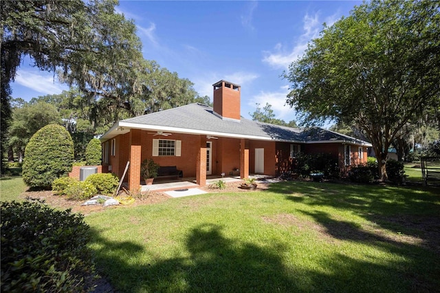 rear view of property featuring a lawn, ceiling fan, and a patio