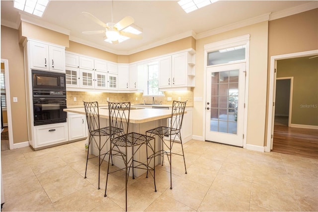 dining area featuring ceiling fan, crown molding, light tile patterned floors, and sink