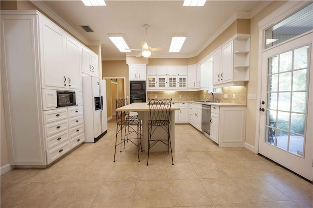 kitchen with black appliances, a kitchen breakfast bar, sink, a kitchen island, and white cabinetry