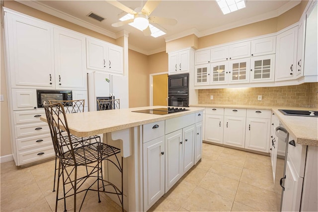 kitchen with black appliances, a kitchen island, and white cabinetry