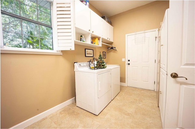 washroom featuring washing machine and dryer, light tile patterned floors, and cabinets