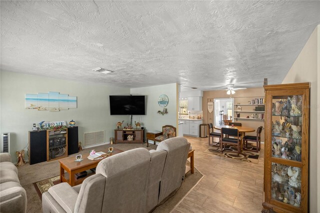 living room with ceiling fan and a textured ceiling