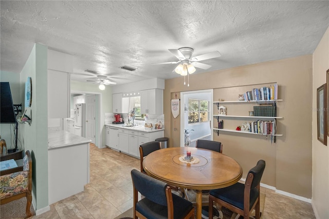 tiled dining space featuring ceiling fan and a textured ceiling