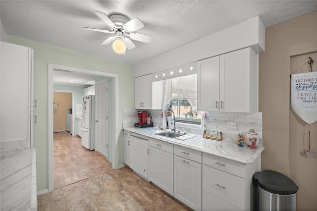 kitchen featuring white appliances, sink, a textured ceiling, tasteful backsplash, and white cabinetry