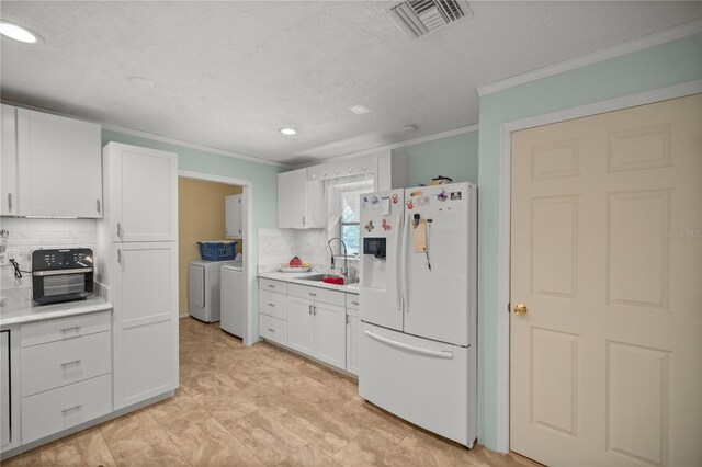 kitchen with backsplash, sink, washing machine and dryer, white fridge with ice dispenser, and white cabinetry