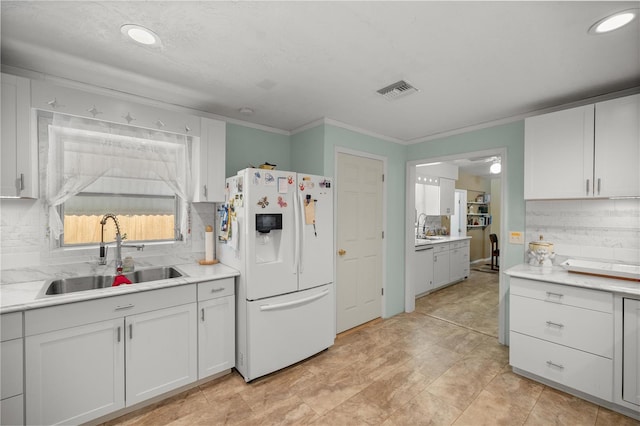 kitchen with backsplash, white cabinetry, white fridge with ice dispenser, and sink