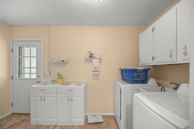 laundry area with cabinets, a textured ceiling, and washer and clothes dryer