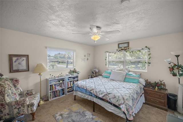 bedroom with ceiling fan, light carpet, and a textured ceiling