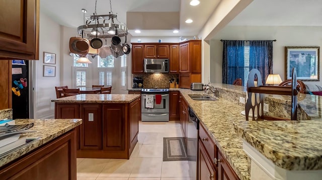 kitchen with a center island, sink, stainless steel appliances, light stone counters, and light tile patterned flooring