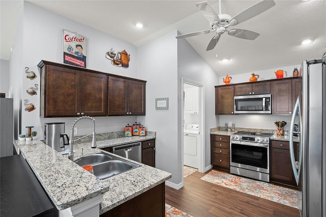 kitchen with kitchen peninsula, appliances with stainless steel finishes, dark hardwood / wood-style flooring, and washer / clothes dryer