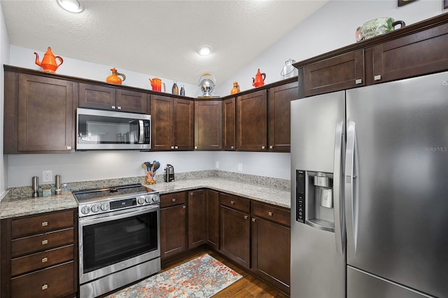 kitchen featuring light stone countertops, dark hardwood / wood-style flooring, a textured ceiling, lofted ceiling, and appliances with stainless steel finishes