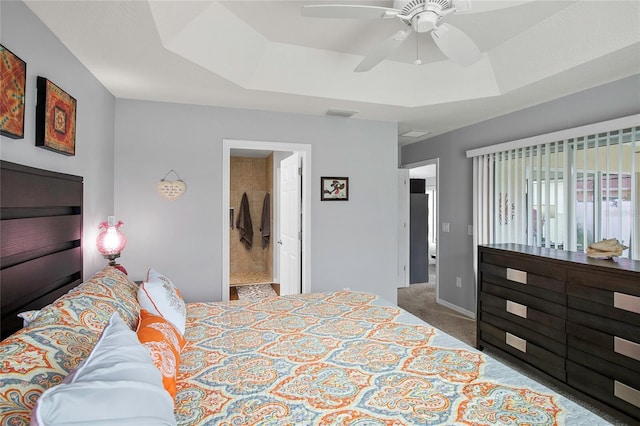 carpeted bedroom with a raised ceiling and ceiling fan