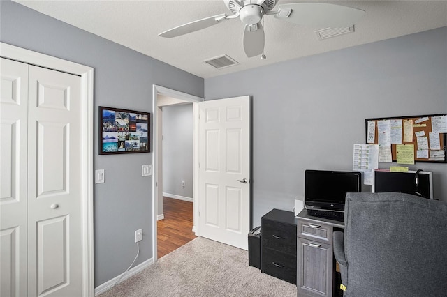 office space featuring a textured ceiling, light colored carpet, and ceiling fan