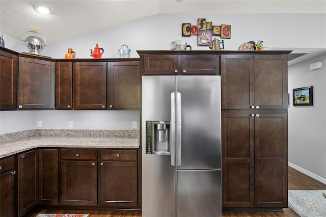 kitchen featuring vaulted ceiling, stainless steel fridge, light stone counters, dark hardwood / wood-style flooring, and dark brown cabinetry