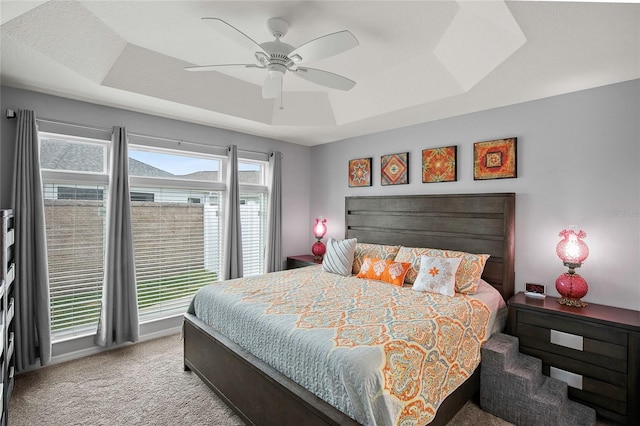 bedroom with a tray ceiling, ceiling fan, and light colored carpet