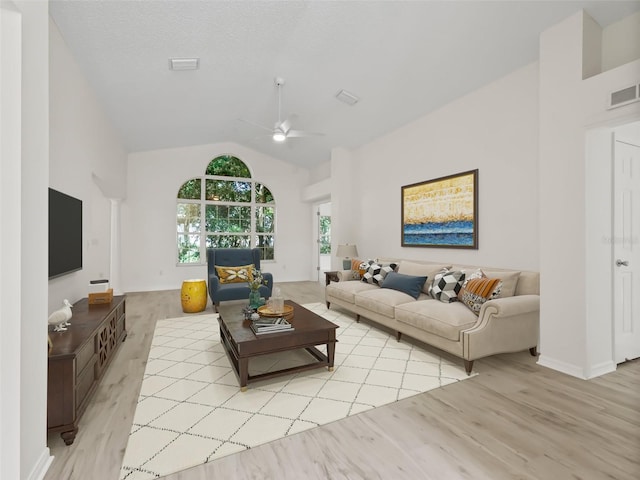 living room with a textured ceiling, ceiling fan, light hardwood / wood-style flooring, and vaulted ceiling