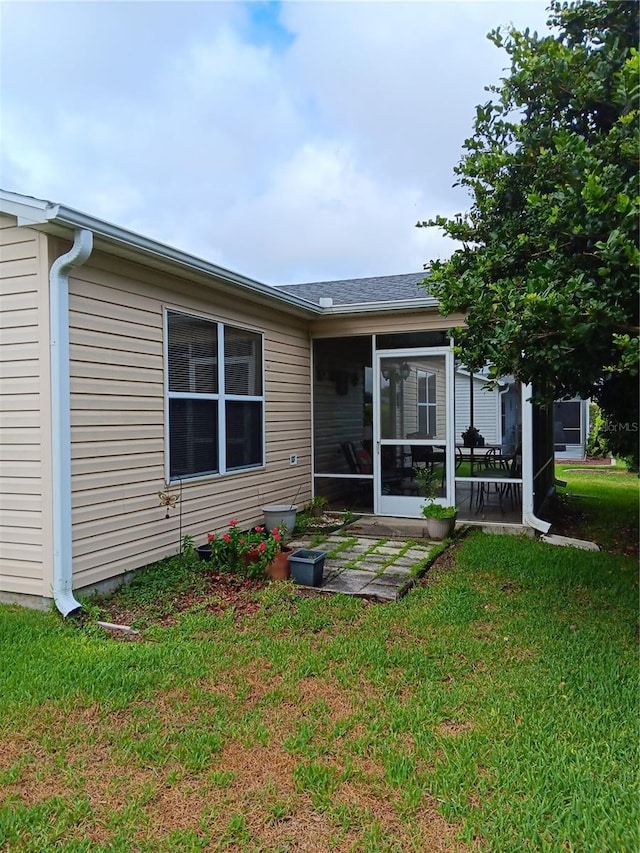 back of house featuring a lawn and a sunroom