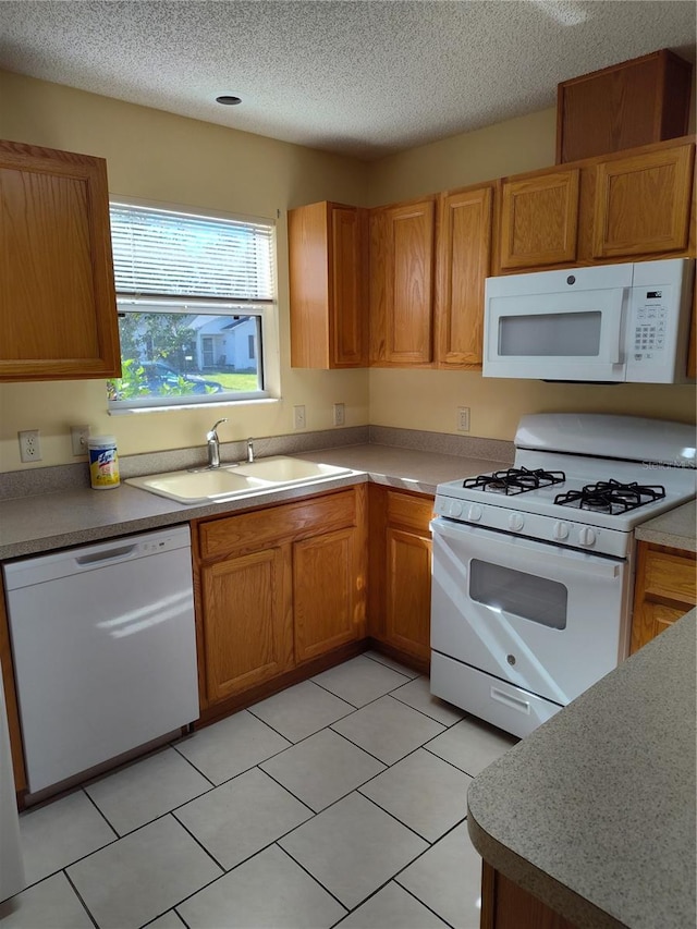 kitchen with sink, white appliances, a textured ceiling, and light tile patterned flooring