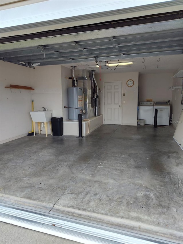 garage with washer and dryer, water heater, and sink