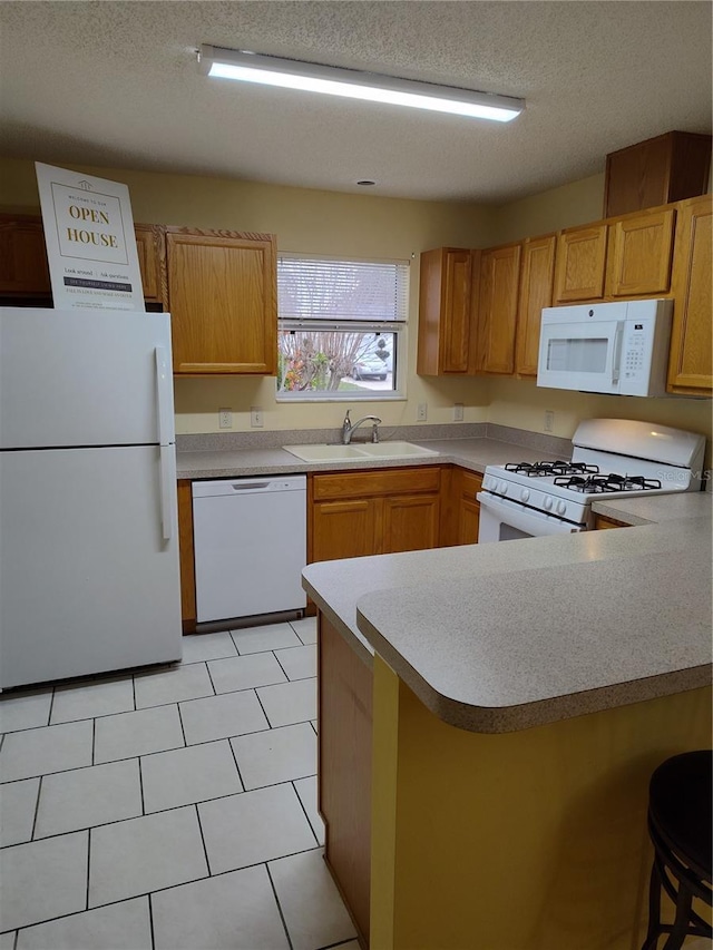 kitchen with white appliances, kitchen peninsula, a textured ceiling, a kitchen bar, and sink