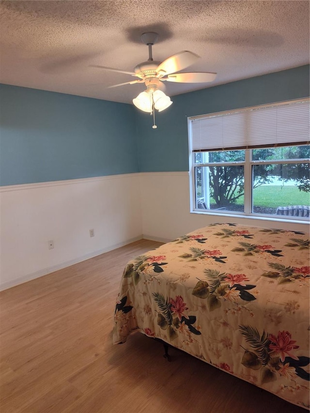 unfurnished bedroom with a textured ceiling, ceiling fan, and light hardwood / wood-style flooring