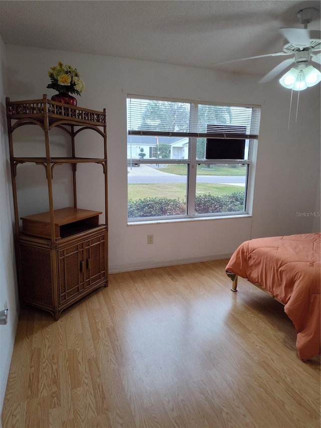 bedroom with ceiling fan, light hardwood / wood-style floors, and a textured ceiling