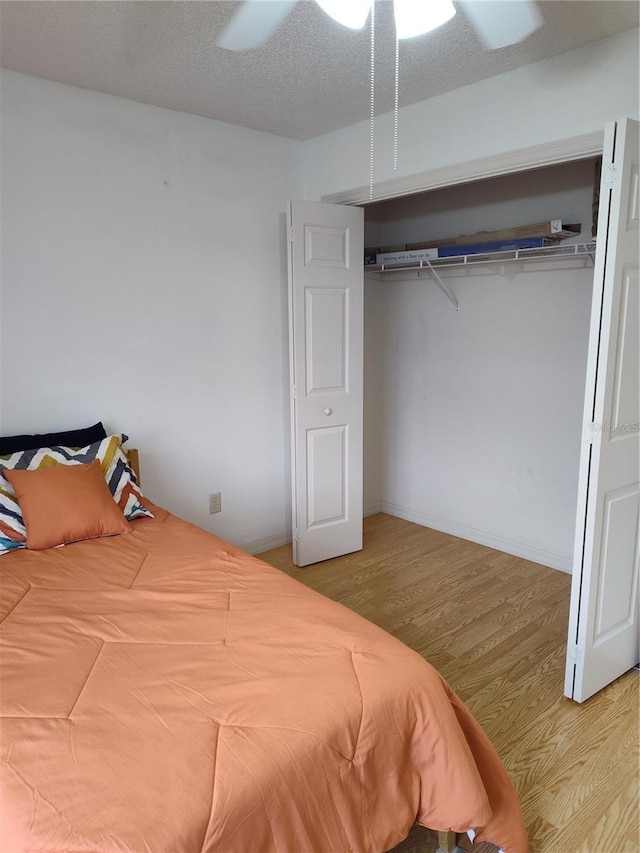 bedroom featuring wood-type flooring, a closet, ceiling fan, and a textured ceiling