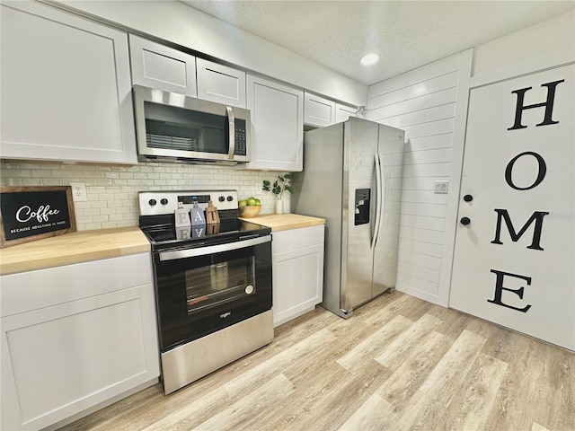 kitchen featuring white cabinetry, stainless steel appliances, a textured ceiling, wood counters, and light wood-type flooring