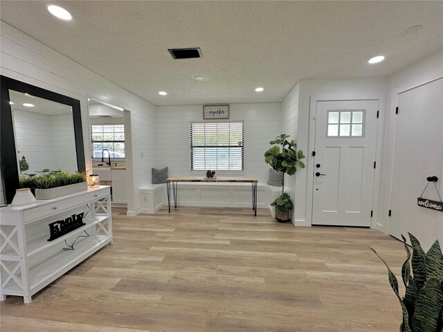 entryway with a textured ceiling and light hardwood / wood-style floors