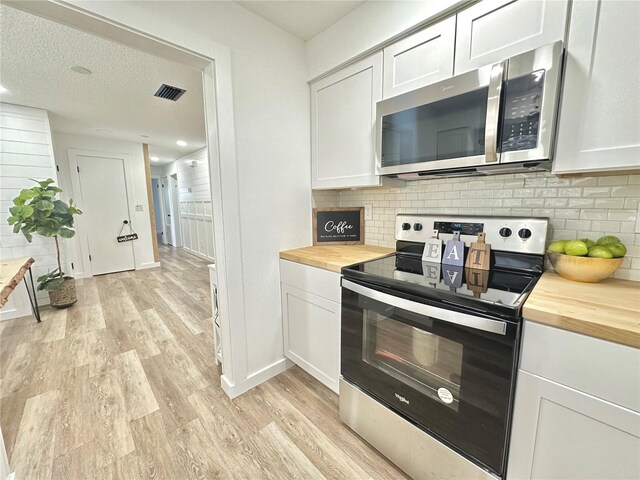 kitchen featuring appliances with stainless steel finishes, butcher block counters, and white cabinets